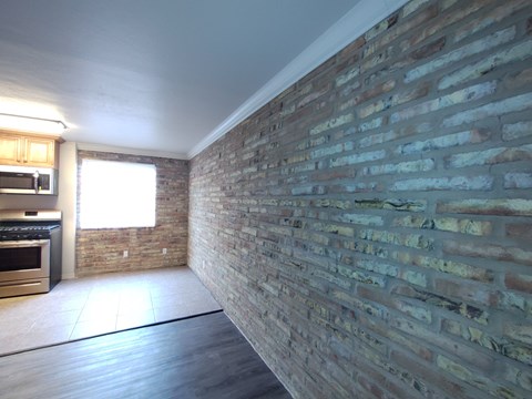 A kitchen with a brick wall and wooden floors.